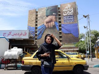 Teherán. Una mujer iraní pasa frente a un cartel con propaganda, que proclama el dominio de ese Gobierno sobre el Estrecho de Ormuz. EFE/A. Taherkenareh
