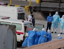 Trabajadores de salud con trajes de protección evacúan pacientes del crucero en una ambulancia en Cabo Verde. AP / M. Apawu