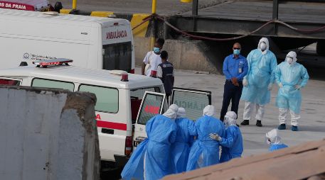 Trabajadores de salud con trajes de protección evacúan pacientes del crucero en una ambulancia en Cabo Verde. AP / M. Apawu