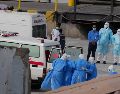 Trabajadores de salud con trajes de protección evacúan pacientes del crucero en una ambulancia en Cabo Verde. AP / M. Apawu