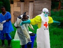 Un trabajador sanitario le rocía desinfectante a su colega tras trabajar en un centro de tratamiento del ébola en Beni, en el este de la República Democrática del Congo. AP/ARCHIVO