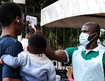 Un funcionario de salud utiliza un termómetro para tomar la temperatura a las personas frente al Hospital Musulmán de Kibuli, en Kampala, Uganda. AP/H. Nalwadda