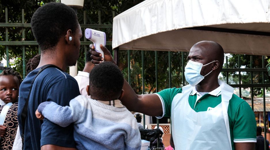 Un funcionario de salud utiliza un termómetro para tomar la temperatura a las personas frente al Hospital Musulmán de Kibuli, en Kampala, Uganda. AP/H. Nalwadda