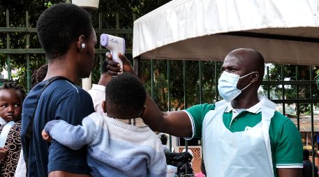 Un funcionario de salud utiliza un termómetro para tomar la temperatura a las personas frente al Hospital Musulmán de Kibuli, en Kampala, Uganda. AP/H. Nalwadda