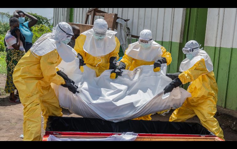 Trabajadores de la Cruz Roja colocan en un ataúd el cuerpo de una persona que murió de ébola, en un centro de salud en Rwampara, Congo. AP/M. Sawasawa