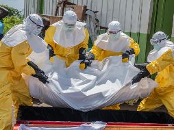 Trabajadores de la Cruz Roja colocan en un ataúd el cuerpo de una persona que murió de ébola, en un centro de salud en Rwampara, Congo. AP/M. Sawasawa