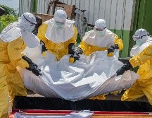 Trabajadores de la Cruz Roja colocan en un ataúd el cuerpo de una persona que murió de ébola, en un centro de salud en Rwampara, Congo. AP/M. Sawasawa