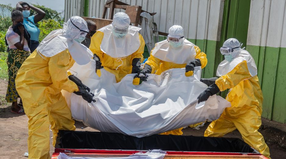 Trabajadores de la Cruz Roja colocan en un ataúd el cuerpo de una persona que murió de ébola, en un centro de salud en Rwampara, Congo. AP/M. Sawasawa
