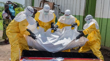 Trabajadores de la Cruz Roja colocan en un ataúd el cuerpo de una persona que murió de ébola, en un centro de salud en Rwampara, Congo. AP/M. Sawasawa