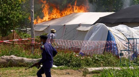 Un guardia de seguridad corre frente a un centro de tratamiento del ébola en llamas en Rwampara, República Democrática del Congo. AP/D. Lotsima