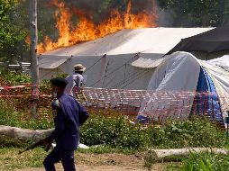 Un guardia de seguridad corre frente a un centro de tratamiento del ébola en llamas en Rwampara, República Democrática del Congo. AP/D. Lotsima