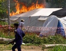 Un guardia de seguridad corre frente a un centro de tratamiento del ébola en llamas en Rwampara, República Democrática del Congo. AP/D. Lotsima