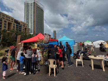 Personas desplazadas por la guerra entre Israel y Hezbolá se reúnen frente a una pequeña panadería, en un asentamiento de tiendas de campaña junto al puerto de Beirut, Líbano. AP/H. Malla