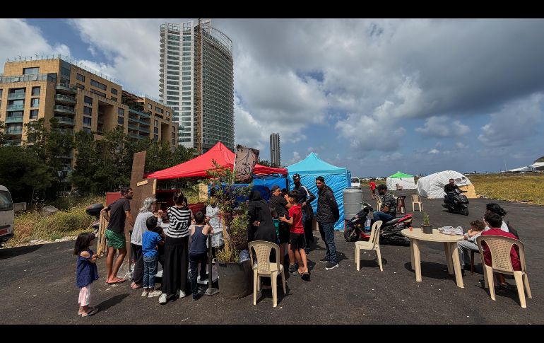 Personas desplazadas por la guerra entre Israel y Hezbolá se reúnen frente a una pequeña panadería, en un asentamiento de tiendas de campaña junto al puerto de Beirut, Líbano. AP/H. Malla