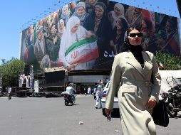 Una mujer camina junto a una enorme valla publicitaria en una calle de Teherán, Irán, este lunes. A pesar del optimismo, la guerra con Estados Unidos parece lejos de terminar. EFE/A. Taherkenareh