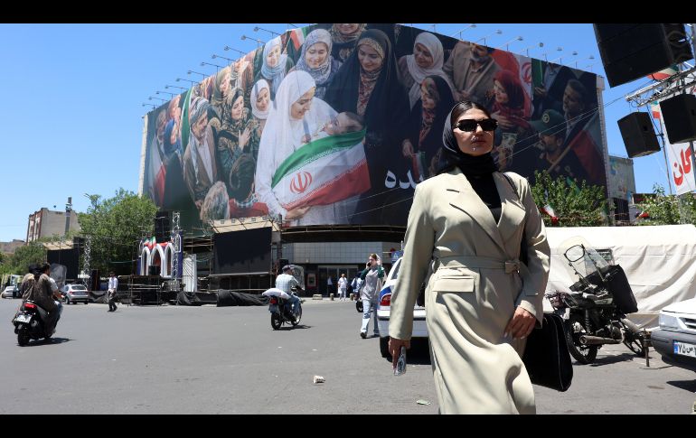 Una mujer camina junto a una enorme valla publicitaria en una calle de Teherán, Irán, este lunes. A pesar del optimismo, la guerra con Estados Unidos parece lejos de terminar. EFE/A. Taherkenareh
