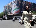 Una mujer camina junto a una enorme valla publicitaria en una calle de Teherán, Irán, este lunes. A pesar del optimismo, la guerra con Estados Unidos parece lejos de terminar. EFE/A. Taherkenareh