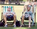 Dos ingleses buscan descansar en un parque público, ante las inusuales condiciones que enfrenta la ciudad. EFE