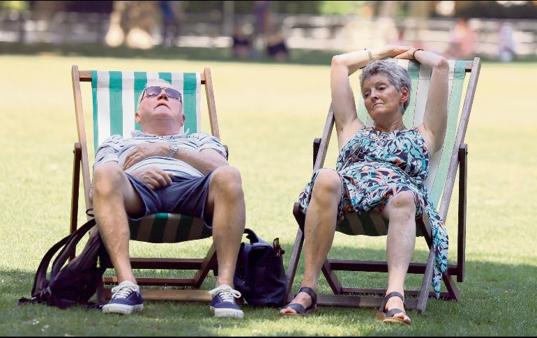 Dos ingleses buscan descansar en un parque público, ante las inusuales condiciones que enfrenta la ciudad. EFE