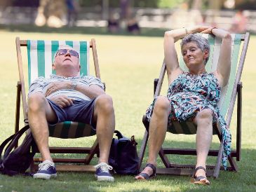 Dos ingleses buscan descansar en un parque público, ante las inusuales condiciones que enfrenta la ciudad. EFE