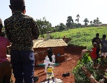 Trabajadores médicos portan trajes de protección mientras son desinfectados previo al entierro de una víctima de ébola, en Mongbwalu, en la provincia de Ituri, en el Congo. XINHUA/STR