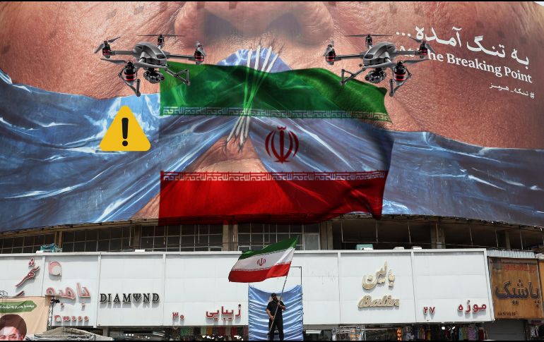Un hombre con una bandera de Irán en Teherán debajo de un espectacular 