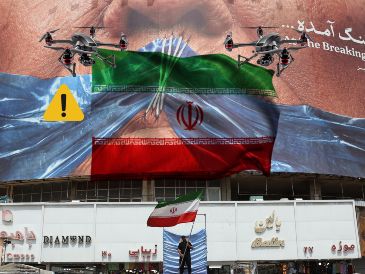Un hombre con una bandera de Irán en Teherán debajo de un espectacular "antiEstados Unidos". EFE / EPA / ABEDIN TAHERKENAREH