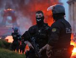 Un automóvil arde y estallan fuegos artificiales mientras la policía observa a los aficionados del PSG celebrar en París. AP/T. Padilla