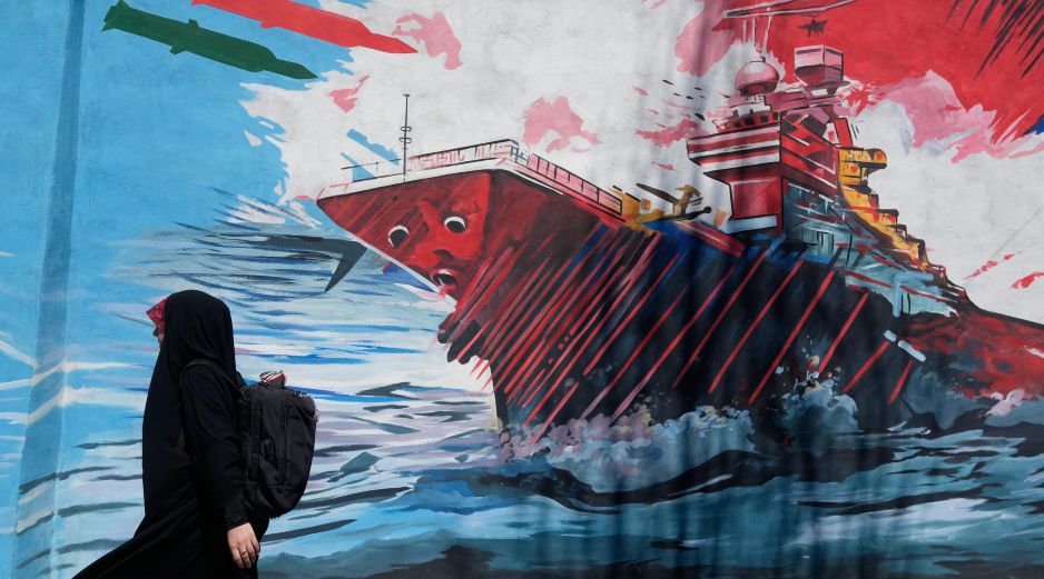 Una mujer pasa junto a un mural que muestra un portaaviones estadounidense bajo ataque en el centro de Teherán, Irán, el lunes 8 de junio de 2026. AP/Vahid Salemi