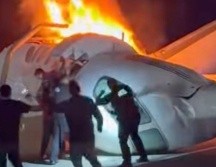 Un pasajero, en la parte superior de la imagen, salta de un avión que se estrelló en una autopista de Texas mientras otras personas ayudan. AP/Z. Garza
