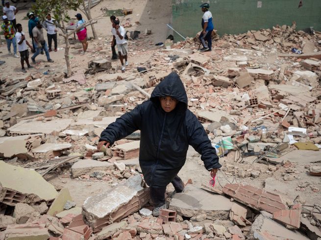 Un niño camina este jueves, entre los escombros de edificios afectados por los terremotos en La Guaira, Venezuela. EFE/ R. Peña