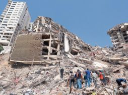 Un grupo de personas contemplan los escombros de edificios derrumbados tras el sismo. XINHUA