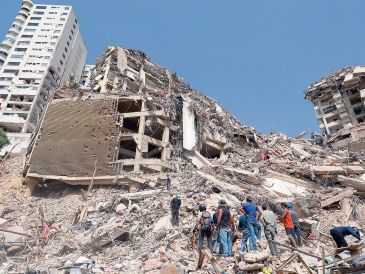 Un grupo de personas contemplan los escombros de edificios derrumbados tras el sismo. XINHUA