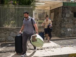 Personas salen de un edificio con pertenencias y mascotas este jueves, en el municipio Chacao en Caracas. EFE/B. Vergara