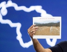 El presidente del Parlamento, Jorge Rodríguez, sostiene una imagen del cementerio La Esperanza durante una rueda de prensa este sábado. EFE/R. Peña