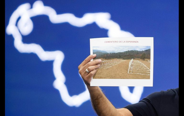 El presidente del Parlamento, Jorge Rodríguez, sostiene una imagen del cementerio La Esperanza durante una rueda de prensa este sábado. EFE/R. Peña