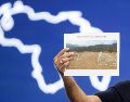 El presidente del Parlamento, Jorge Rodríguez, sostiene una imagen del cementerio La Esperanza durante una rueda de prensa este sábado. EFE/R. Peña