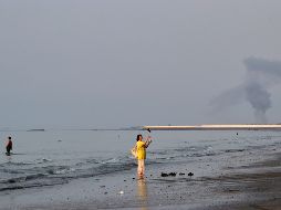 Una mujer cerca de la orilla del mar a lo largo del estrecho de Ormuz, mientras se levanta una columna de humo tras una explosión, frente a Bandar Abbas, Irán. AP/R. Poudat