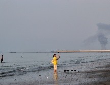 Una mujer cerca de la orilla del mar a lo largo del estrecho de Ormuz, mientras se levanta una columna de humo tras una explosión, frente a Bandar Abbas, Irán. AP/R. Poudat