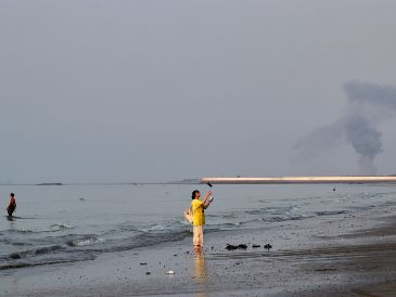 Una mujer cerca de la orilla del mar a lo largo del estrecho de Ormuz, mientras se levanta una columna de humo tras una explosión, frente a Bandar Abbas, Irán. AP/R. Poudat