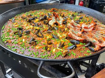 En el Borough Market no existe ni siquiera un espacio con mesas y sillas donde sentarse, y muchos clientes terminan comiendo paella de pie. EFE / L. Campello