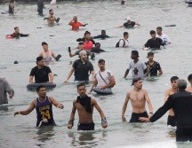 Un grupo de inmigrantes en la playa junto al paso fronterizo del Tarajal en Ceuta este viernes, donde se han registrado violentos enfrentamientos en los perímetros fronterizos durante su intento de acceder desde Marruecos hacia Ceuta y Melilla. EFE/ R. Dris