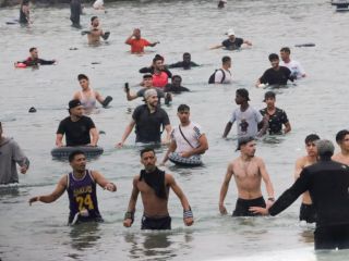 Un grupo de inmigrantes en la playa junto al paso fronterizo del Tarajal en Ceuta este viernes, donde se han registrado violentos enfrentamientos en los perímetros fronterizos durante su intento de acceder desde Marruecos hacia Ceuta y Melilla. EFE/ R. Dris