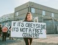 La pancarta que la manifestante sostiene expresa “si debemos elegir entre obedecer o morir, no es un país libre”. EFE