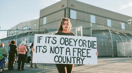 La pancarta que la manifestante sostiene expresa “si debemos elegir entre obedecer o morir, no es un país libre”. EFE