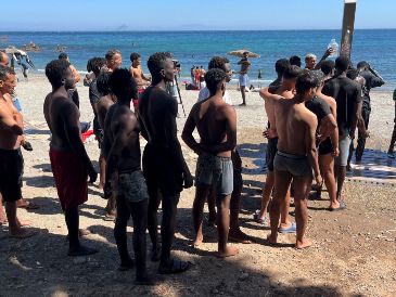 Jóvenes inmigrantes que duermen en la calle hacen fila para bañarse en la playa del Trampolín, tras acceder a Ceuta el pasado jueves. EFE/Reudan