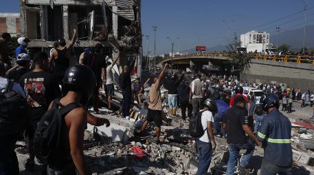 Personas caminan sobre los escombros de un edificio colapsado este lunes, en Cali (Colombia). Al menos 20 edificios sufrieron graves daños por consecuencia del terremoto de magnitud 7,4 que sacudió la mayor parte del país, con epicentro en la zona del Pacífico. EFE/ E. Guzmán