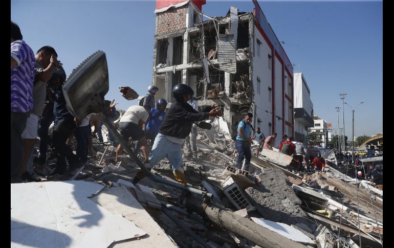 Personas caminan sobre los escombros de un edificio colapsado este lunes, en Cali (Colombia). EFE / E. Guzmán
