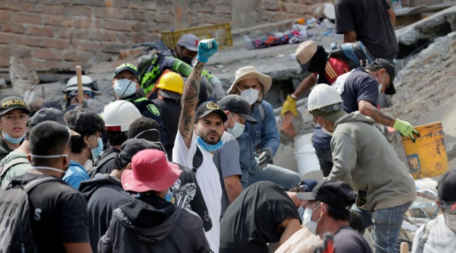 Voluntarios levantan los brazos para pedir silencio durante las labores de búsqueda en edificios derrumbados por el terremoto en Pereira, Colombia. EFE/C. Ortega