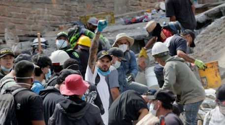 Voluntarios levantan los brazos para pedir silencio durante las labores de búsqueda en edificios derrumbados por el terremoto en Pereira, Colombia. EFE/C. Ortega